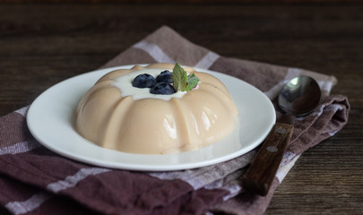 Coffee milk jelly or panna cotta with sour cream, blueberry and mint on a white plate