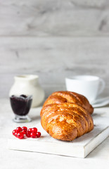 Delicious breakfast with fresh croissants and berries with cup of coffee on a light grey background
