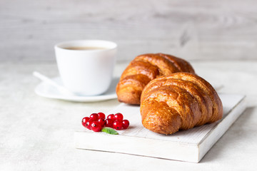 Fresh croissants with red currant on a light grey background