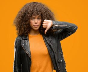 African american woman wearing a leather jacket with angry face, negative sign showing dislike with...