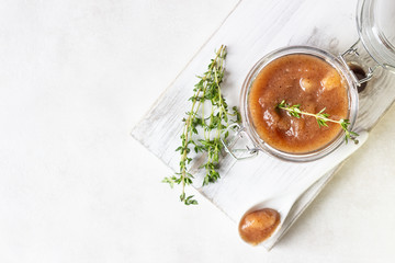 Homemade pear jam in a jar on wooden board on light background. Selective focus, copy space 