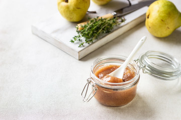 Pear jam, fresh pears and thyme on wooden board on light background.