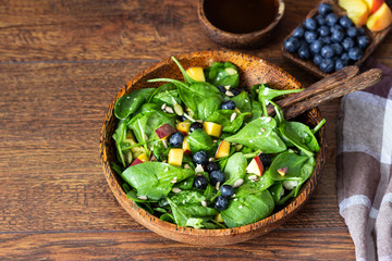 Summer spinach and fruit salad with seeds, mozzarella and balsamic vinegar in a bowl. Summer food concept
