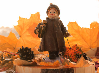 Girl with Christmas gifts makes a transition from autumn to winter season among yellow leaves and cones concept. Copy space