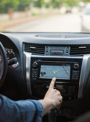 Man touching screen of a GPS navigation system in his car