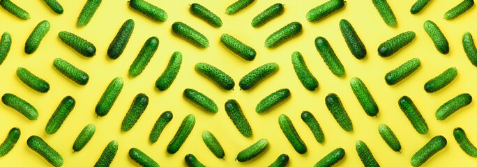 Creative pattern of fresh green cucumbers on yellow background. Top view. Copy space. Minimal...