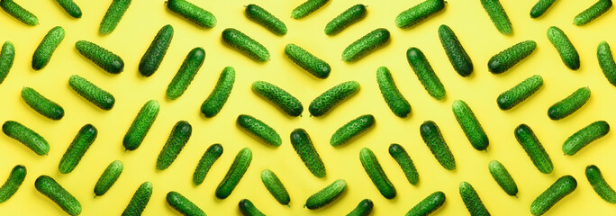 Creative pattern of fresh green cucumbers on yellow background. Top view. Copy space. Minimal design. Vegetarian, vegan, organic food and alkaline meal concept