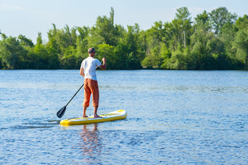 Man sails on a SUP board in large river