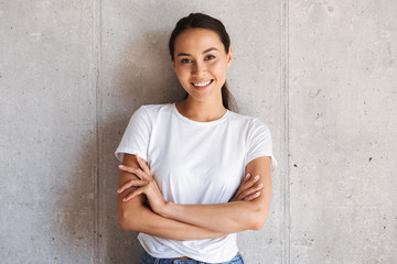Cheerful young asian woman standing with arms folded