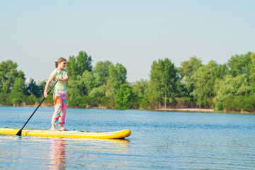 Fototapeta na wymiar Woman sails on a SUP board in large river