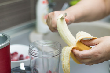Close up of woman preparing banana smoothie.