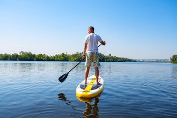 Adult man sails on a SUP board in large river