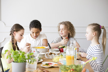 Group of children eating healthy dinner at friend's home