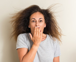 Curled hair brazilian woman cover mouth with hand shocked with shame for mistake, expression of...