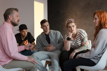 Rebellious teenagers listening to a ginger girl during a meeting of a support group