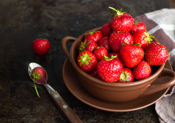 Fresh strawberry in a clay plate on concrete board wooden table.