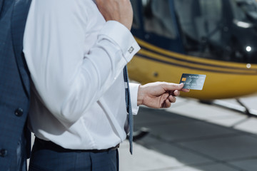 Quick and convenient. The focus being on a platinum credit card in the hands of a young businessman having used it to rent a helicopter