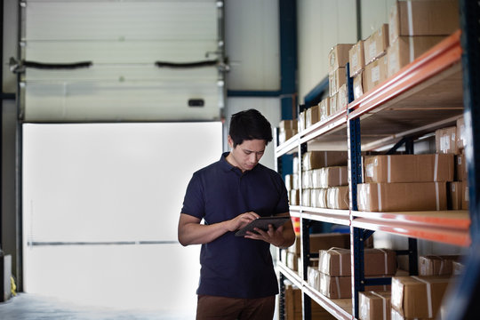 Male working in distribution warehouse with digital tablet