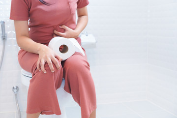 Woman sitting on toilet with diarrhea or constipated pain and toilet paper concept
