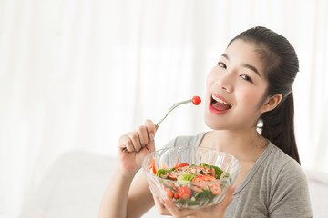 Enjoyed Asian woman eating vegetable salad.