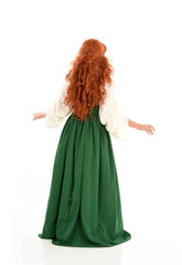 full length portrait of red haired girl wearing long green gown,. standing pose with back to the...