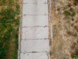 Old concrete slab road in dry and grassy environment, aerial view