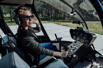 Off to adventures. Gorgeous female helicopter pilot holding a steering wheel and smiling elatedly...