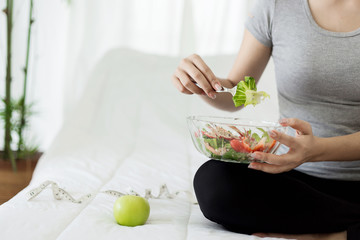 Enjoyed Asian woman eating vegetable salad.