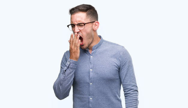 Handsome young elegant man wearing glasses bored yawning tired covering mouth with hand. Restless and sleepiness.