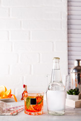 alcohol cocktail with fresh fruits and berries with a bottle of tonic and a place under the text on the bottle on white wooden background