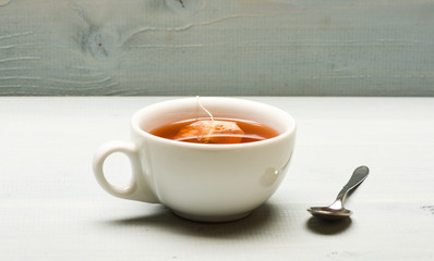 Mug filled with boiling water, teabag and spoon on white background. Mug filled with hot water and...