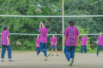 Happiness group of teenage friends playing volleyball in school.