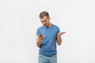 Closeup worried hispanic man looking at his smart phone with anger and confusion isolated on gray...