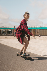 young woman in sunglasses and shirt skating on longboard on street in Portugal