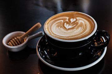 Closeup cappuccino in black ceramic cup,blurry light around.