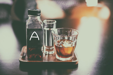 The abstract art design background of coffee bottle and glass of water on wooden tray,blurry light around.