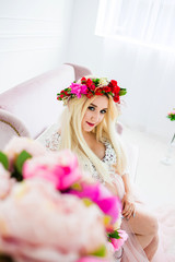 A blond woman in a wreath sitting on a sofa