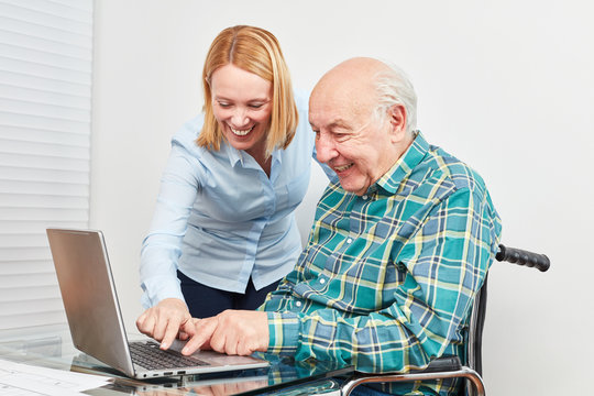 Junge Frau hilft Senior am Laptop Computer