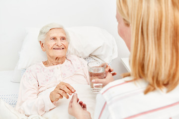 Seniorin nimmt ein Medikament mit Wasser ein