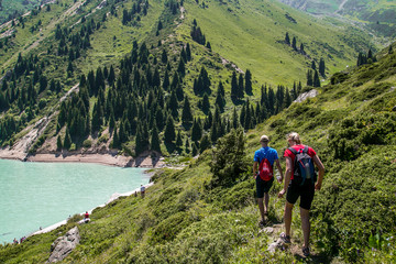 Tourist group in the mountains near the lake Trees,  rocks around the mountain river.  Kyrgyzstan.