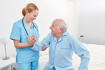 Weibliche Pflegekraft hilft Senior beim Aufstehen