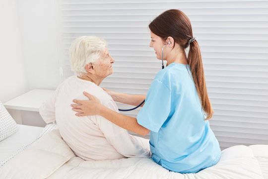 Pflegehilfe mit Stethoskop untersucht Seniorin