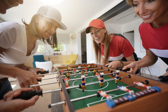 Girls having fun playing foosball at home