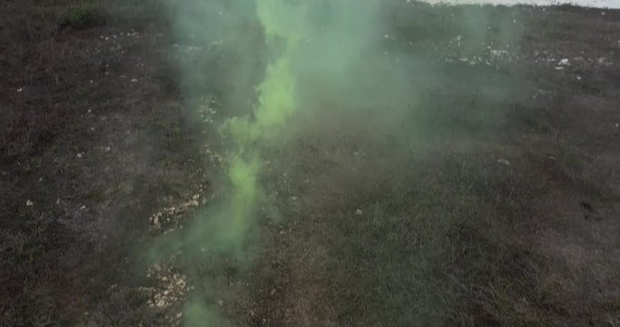 Aerial drone view of beautiful girl with colored smoke playing at the mountain field over ocean and cloudy sky background - video in slow motion