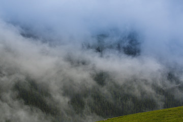 Summer scenery in the Alps with rain and mist clouds