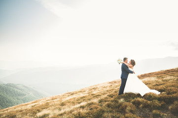 Beautiful gorgeous bride posing to groom and having fun, luxury ceremony at mountains with amazing view, space for text, wedding couple