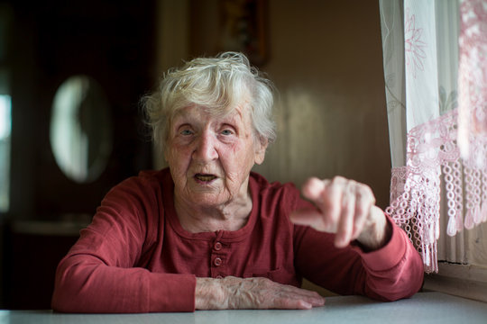 Russian elderly woman emotionally talking sitting at a table at the home.