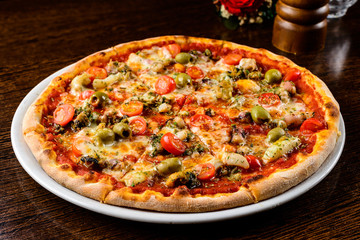 Tasty warm pizza with bacon, tomatoes, cheese and olives on the 