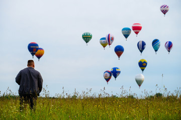 Man standing in the field and looking at colorful hot air balloo © smspsy