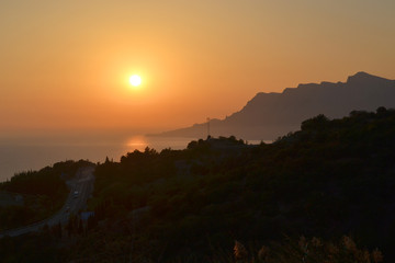 Sunset, setting sun over the sea and mountains
